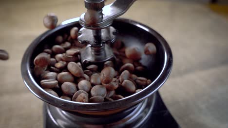 los granos de café caen en el viejo molinillo. cámara lenta con seguimiento de rotación.