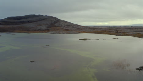 tracking aerial shot of mullaghmore mountain with seasonal lake in foreground. burren