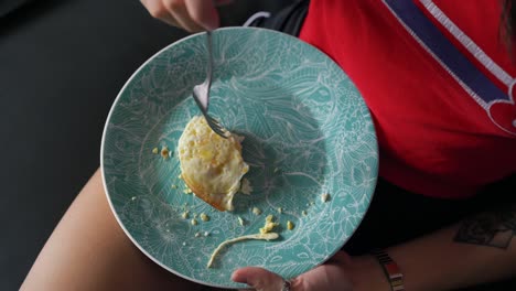 girl eating eggs on the couch, close-up of hand eating food on plate