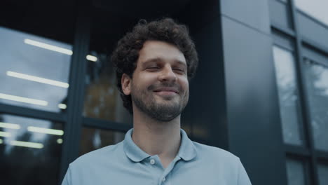 Closeup-smiling-man-teacher-standing-at-school-entrance-looking-distance.