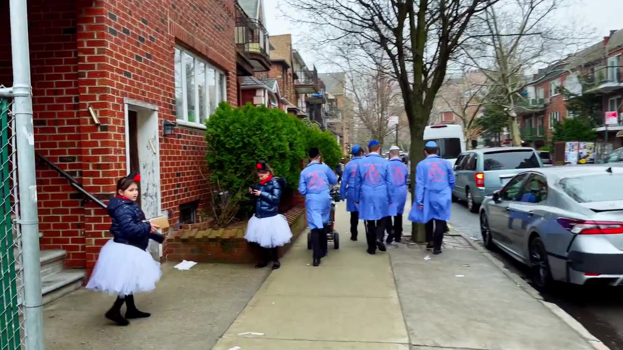 New York, USA, 9 marzo 2022: Uomini in cappotti blu su una strada residenziale di Brooklyn. Uomini in cappotti blu stanno in piedi e camminano vicino a auto parcheggiate su una strada residenziale bagnata di Brooklyn.