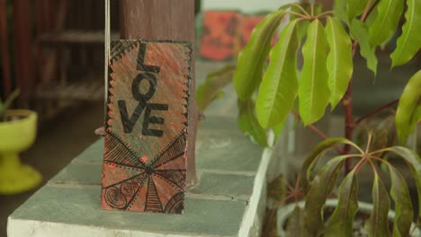 Handmade-'LOVE'-sign-on-a-rustic-wooden-post,-vibrant-leaves-in-foreground,-warm-and-cozy-vibe