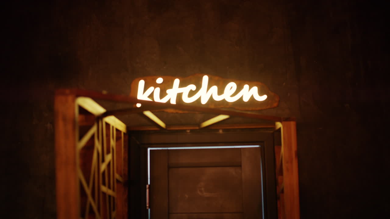Insegna al neon luminosa con la scritta "cucina" sopra una porta in un ambiente interno accogliente.