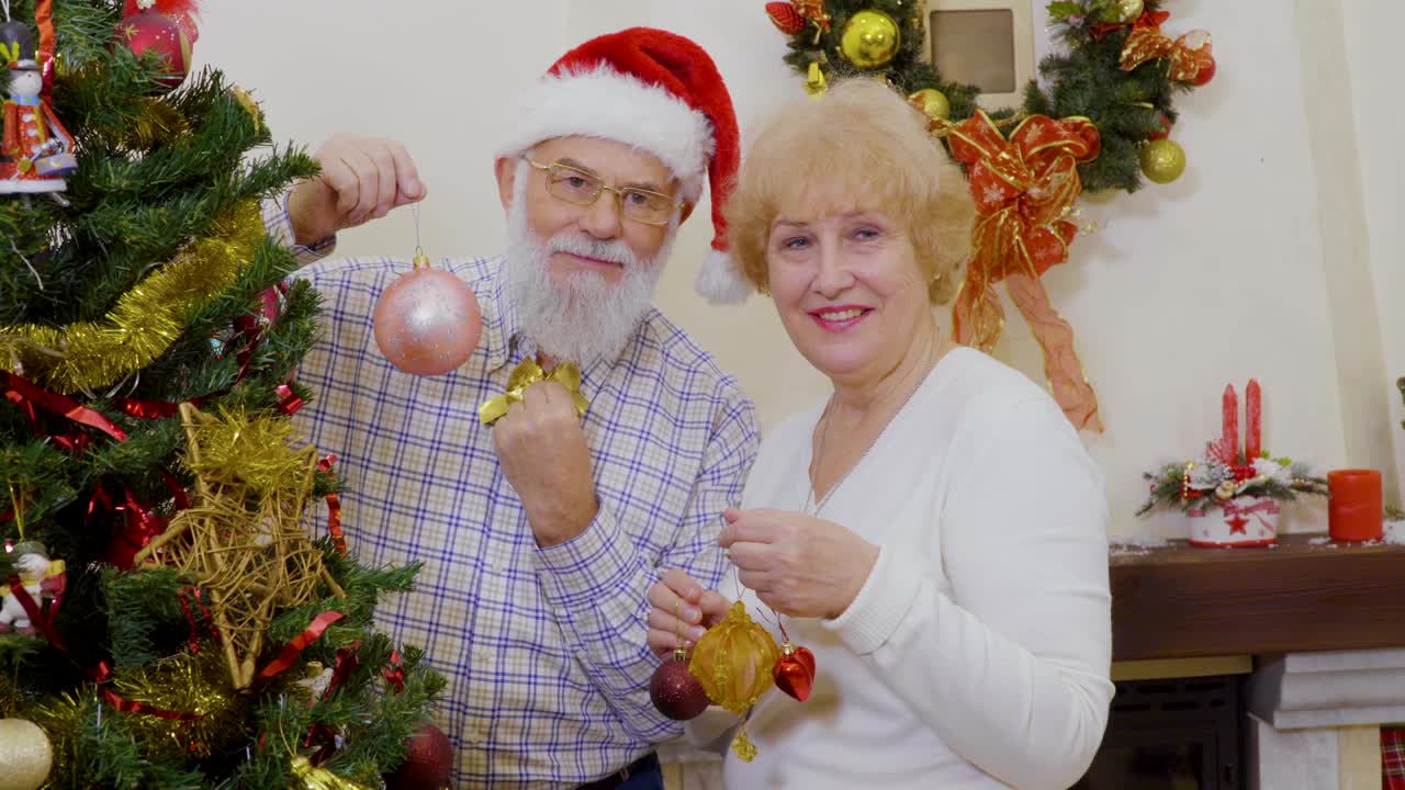 una pareja casada y madura decoran el árbol de navidad en casa.