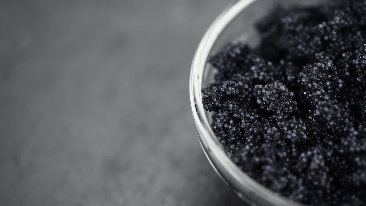 porción de caviar negro girando en un plato (de cerca; en bucle sin costuras)