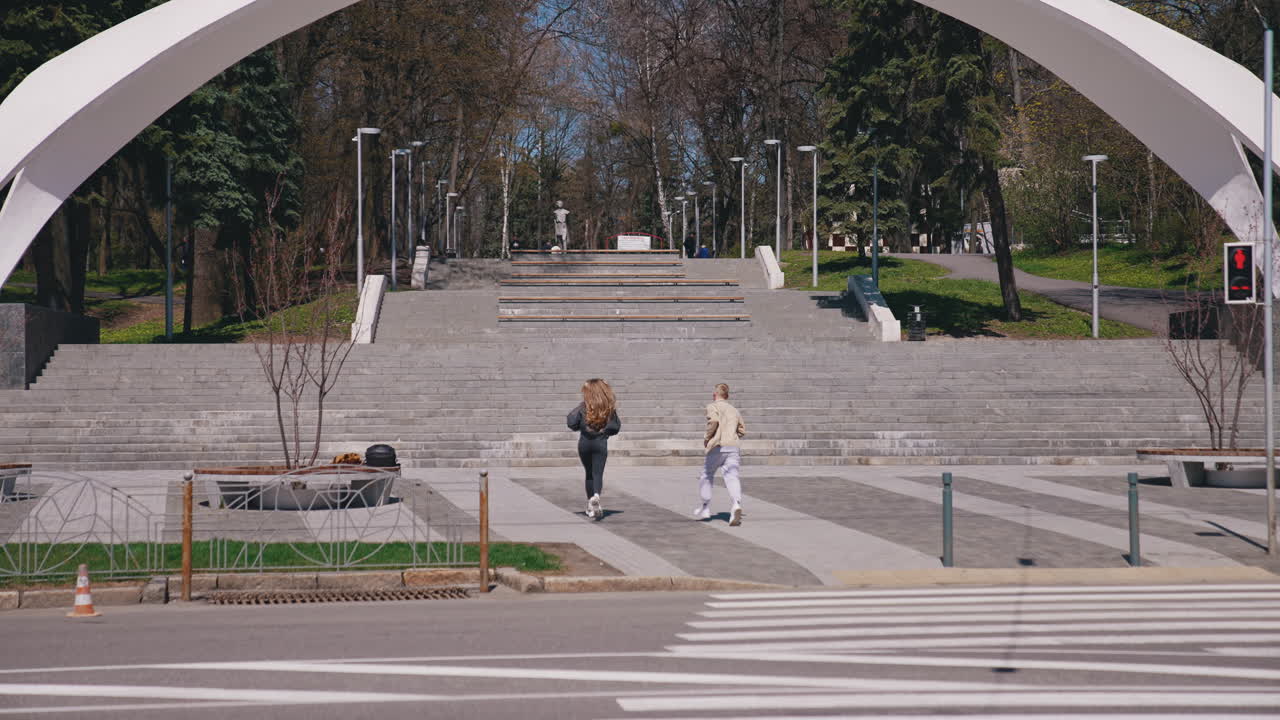 Happy couple running into the park at the stairs. Good looking couple spending time with each other in park in a sunny day. Young people enjoying the time together concept
