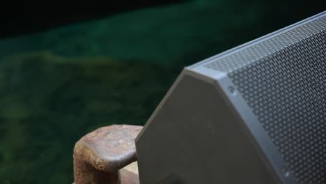 altavoz gris muy cerca de la cámara con agua de fondo