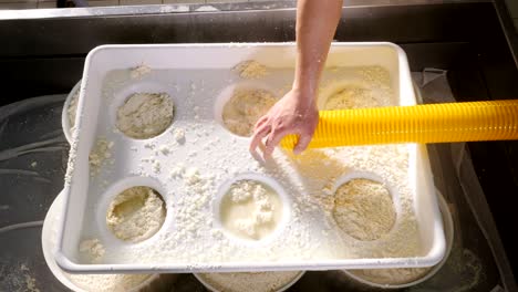 close up on cheese maker putting fresh cheese in the molds- cheese factory