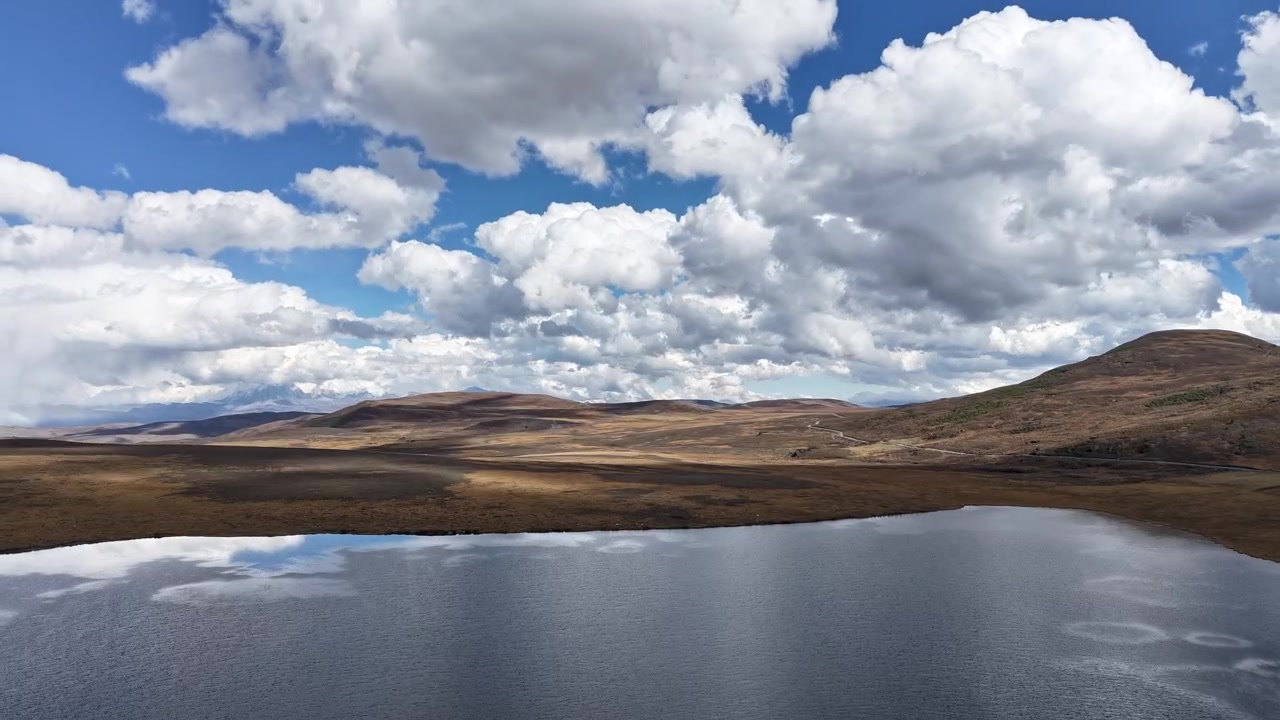 Vista aerea con drone di un remoto lago delle Highlands nel Parco Nazionale di Loch Lomond e The Trossachs, Scozia. Brughiera, dolci colline e acqua calma si estendono sotto nuvole drammatiche