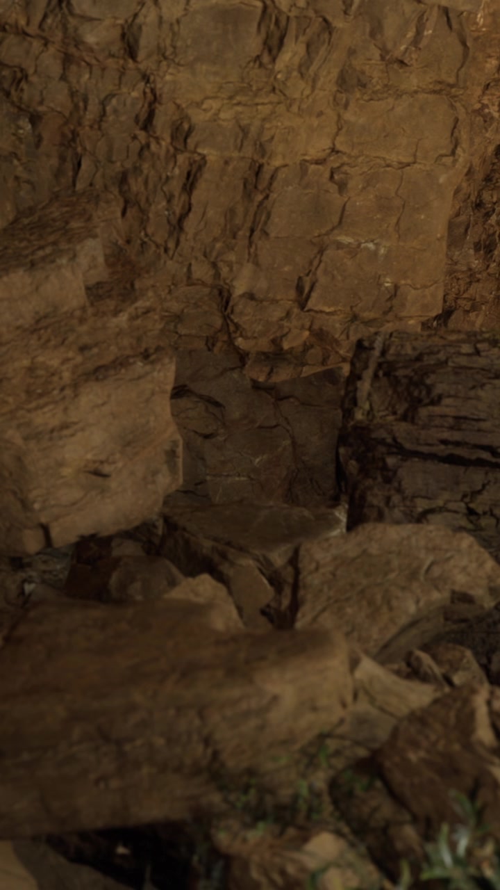 Large rocks scattered in a cave with rough walls and dim light