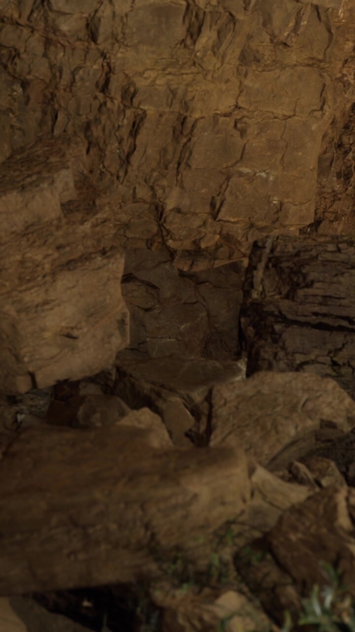 Large rocks scattered in a cave with rough walls and dim light