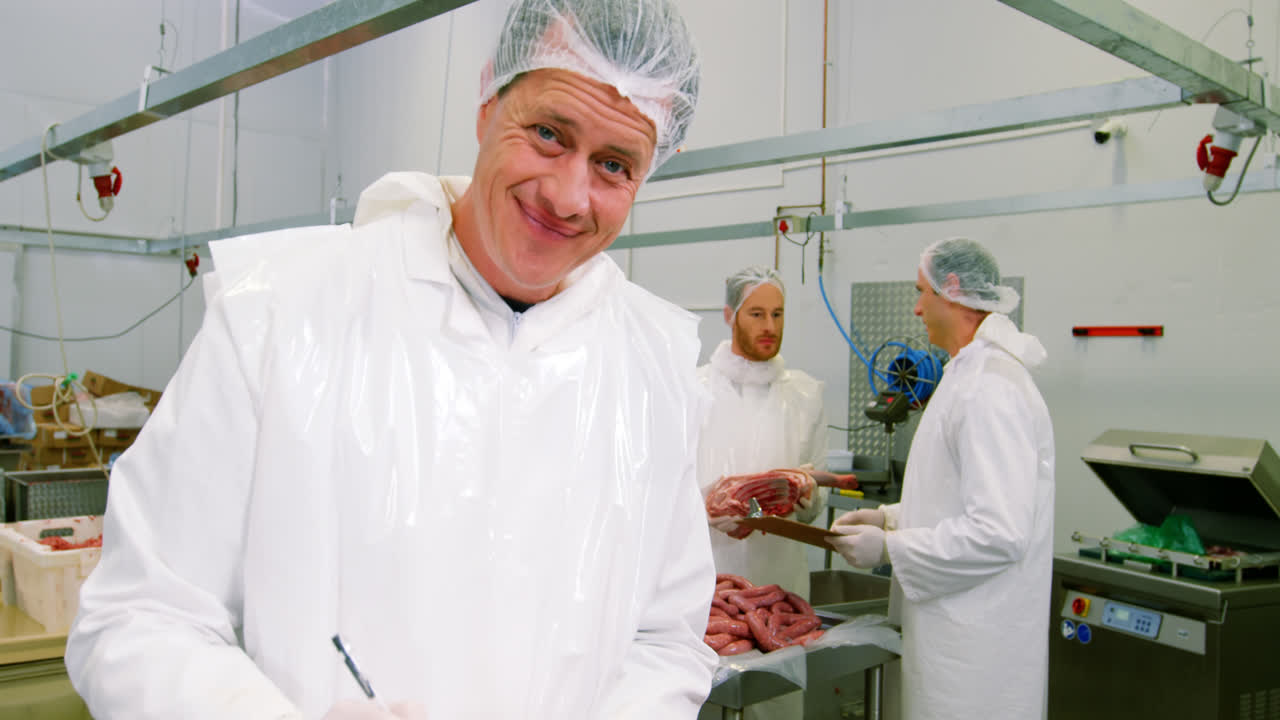 Male butcher maintaining records on clipboard