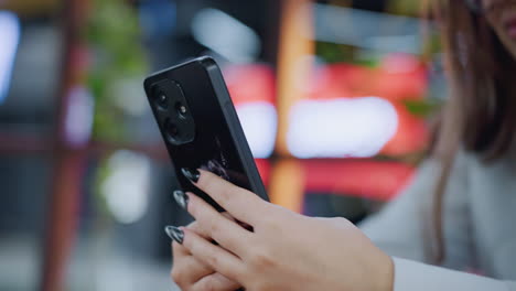 close-up of black painted nails holding iphone with donkey sticker as owner operates it with blurred background, focus on personalized phone case and stylish nails in casual setting