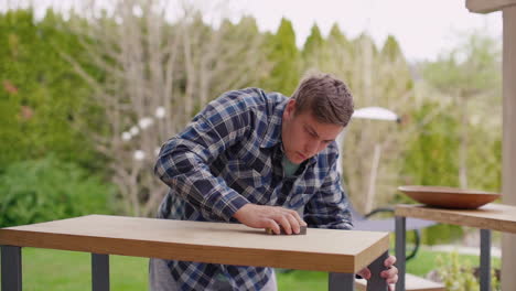 man sanding outdoor wooden table