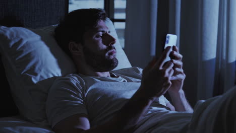 man using phone in bed at night