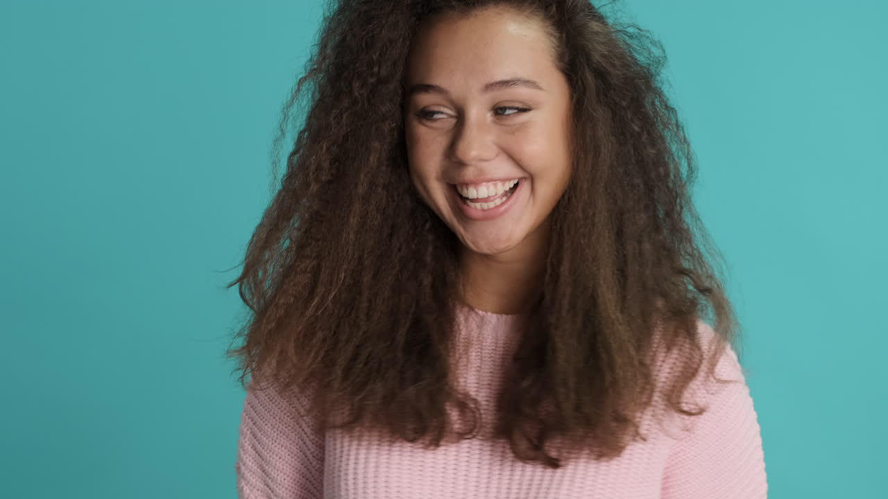 Caucasian curly haired woman making funny faces in front of the camera.