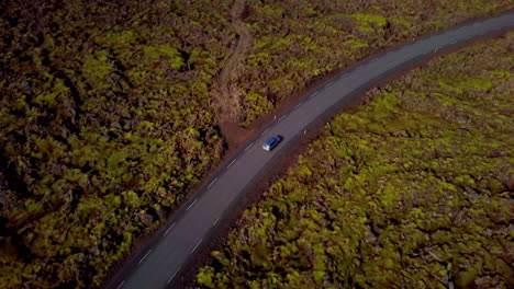 Aerial-view-Top-down-silver-car-driving-down-Grindavík-country-asphalt-road-Iceland