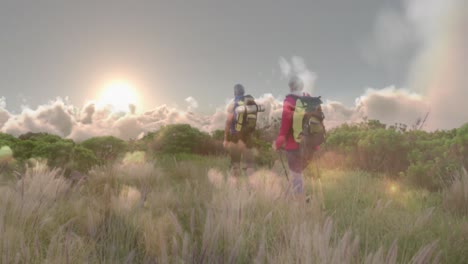 caucasian senior couple hiking in countryside, over fast moving clouds and sunset