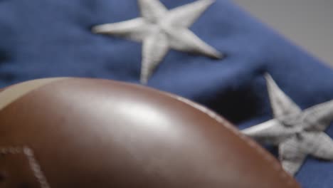 focus pulls from close up shot of american football to stars and stripes flag