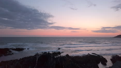 Panorámica-De-Izquierda-A-Derecha-De-Las-Olas-Rompiendo-Contra-Una-Playa-De-Arena-Al-Atardecer