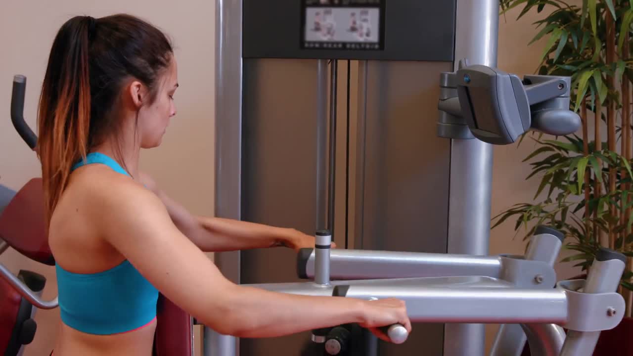 Mujer usando máquina de pesas en el gimnasio