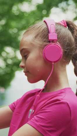a young girl enjoys music outdoors: capturing joy and confidence with vibrant pink headphones in a serene natural setting