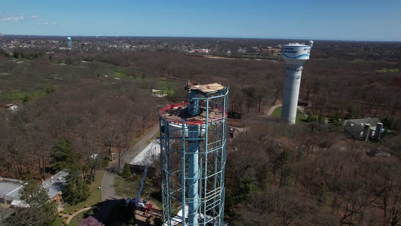 una vista aérea de una torre de agua siendo desmantelada en un día soleado en long island, nueva york