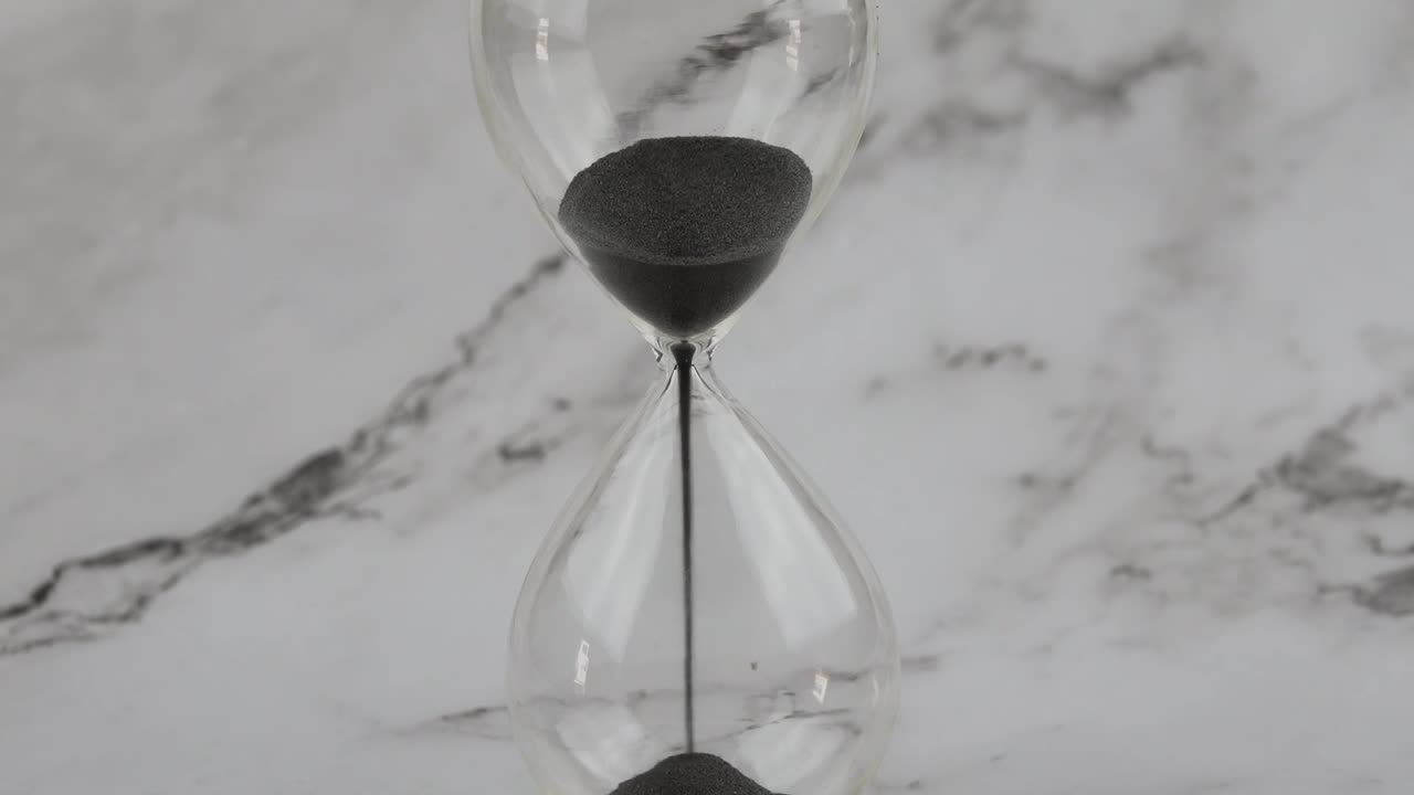 Hour glass with sands flowing through the stem-1