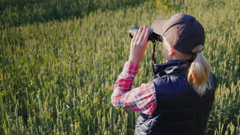 una cazadora mira a lo lejos a través de binoculares vista trasera video 4k