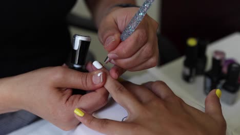 anonymous beautician applying lacquer on female client nails