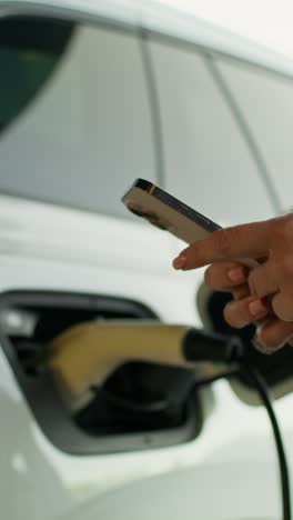 woman charging electric car using smartphone