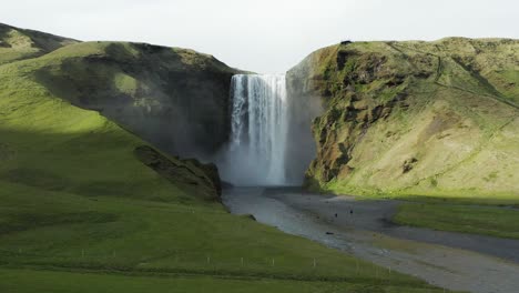 Mächtiger-Skógafoss-wasserfall-Mit-Magischem-Sonnenlicht,-Das-Den-Hügel-Beleuchtet