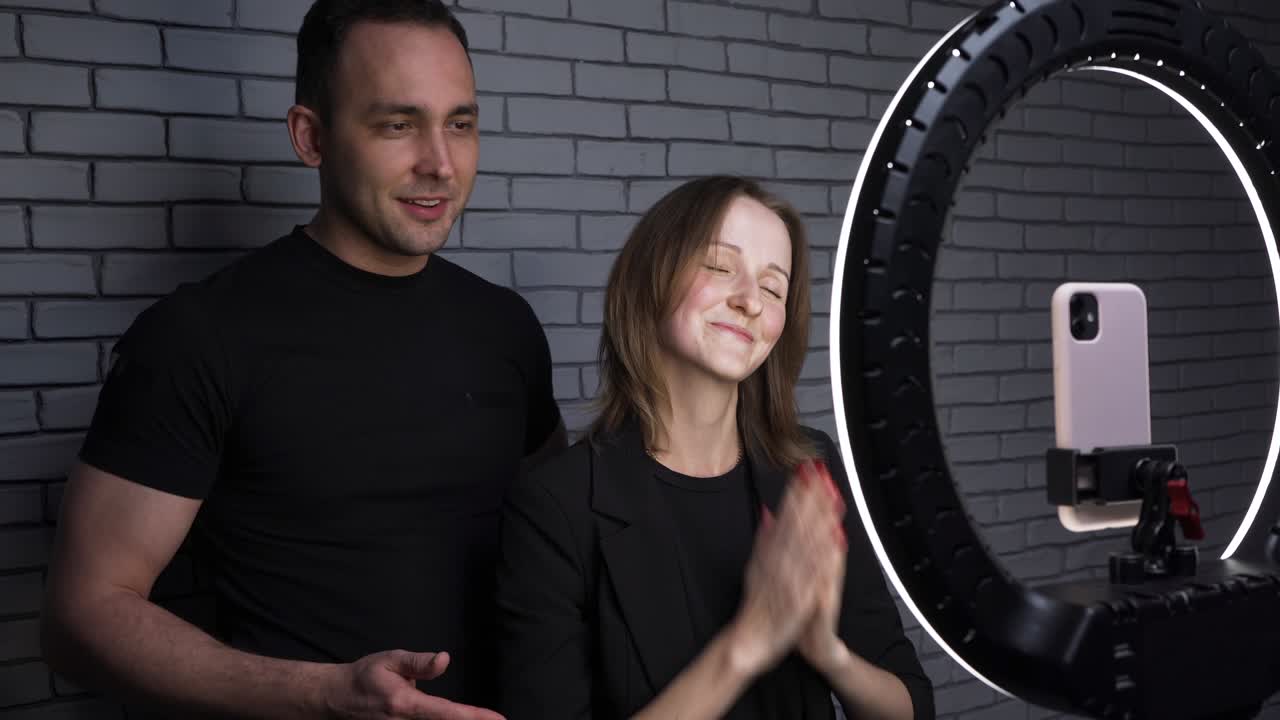 disparo de una pareja con un teléfono inteligente en el fondo de la pared de ladrillo