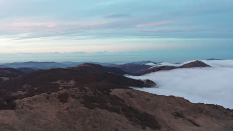 Neblige-Berglandschaft-Im-Morgengrauen-Mit-Rollenden-Wolken-Und-Gipfeln