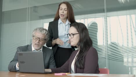 tres hombres de negocios serios viendo la presentación en la computadora portátil