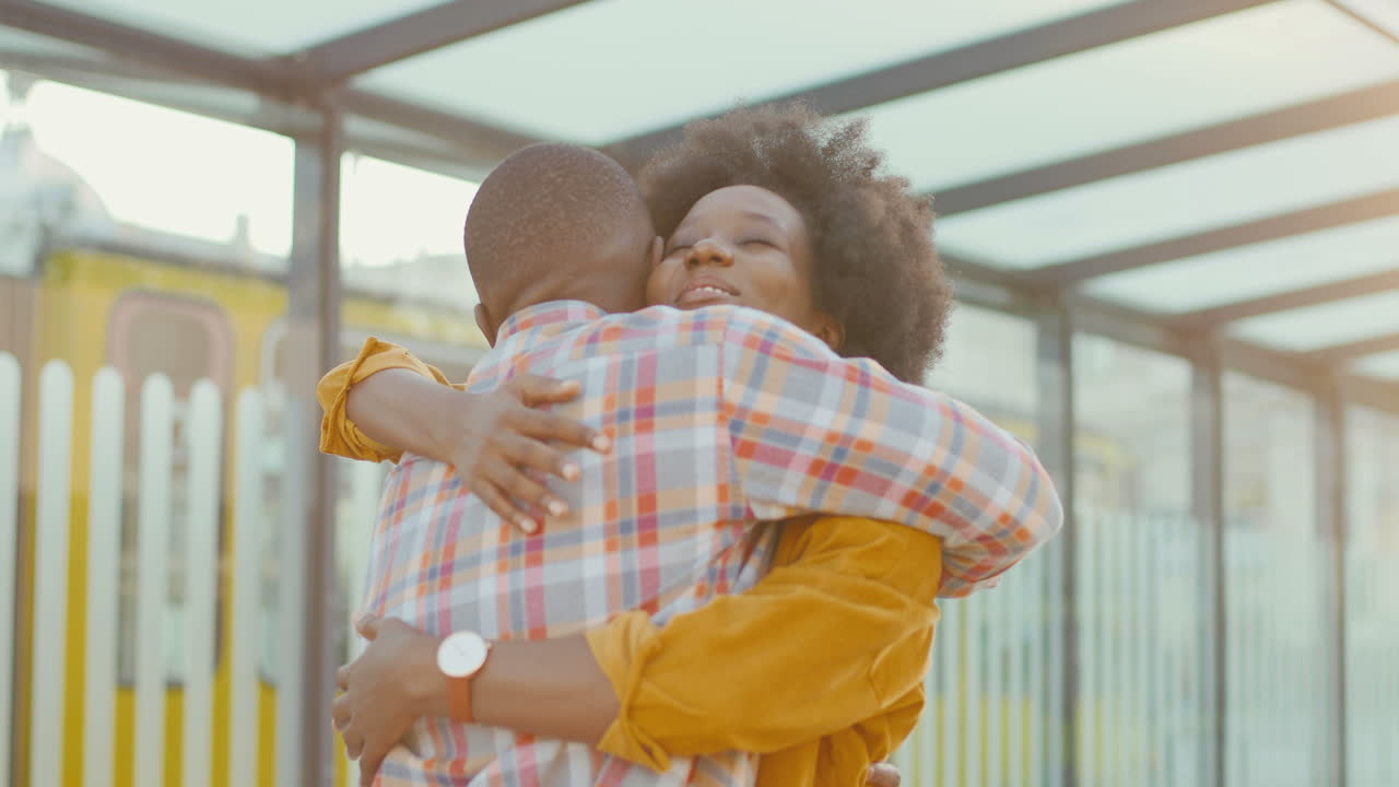 feliz pareja joven afroamericana reunida en la estación de tren y abrazándose en un agradable día de verano