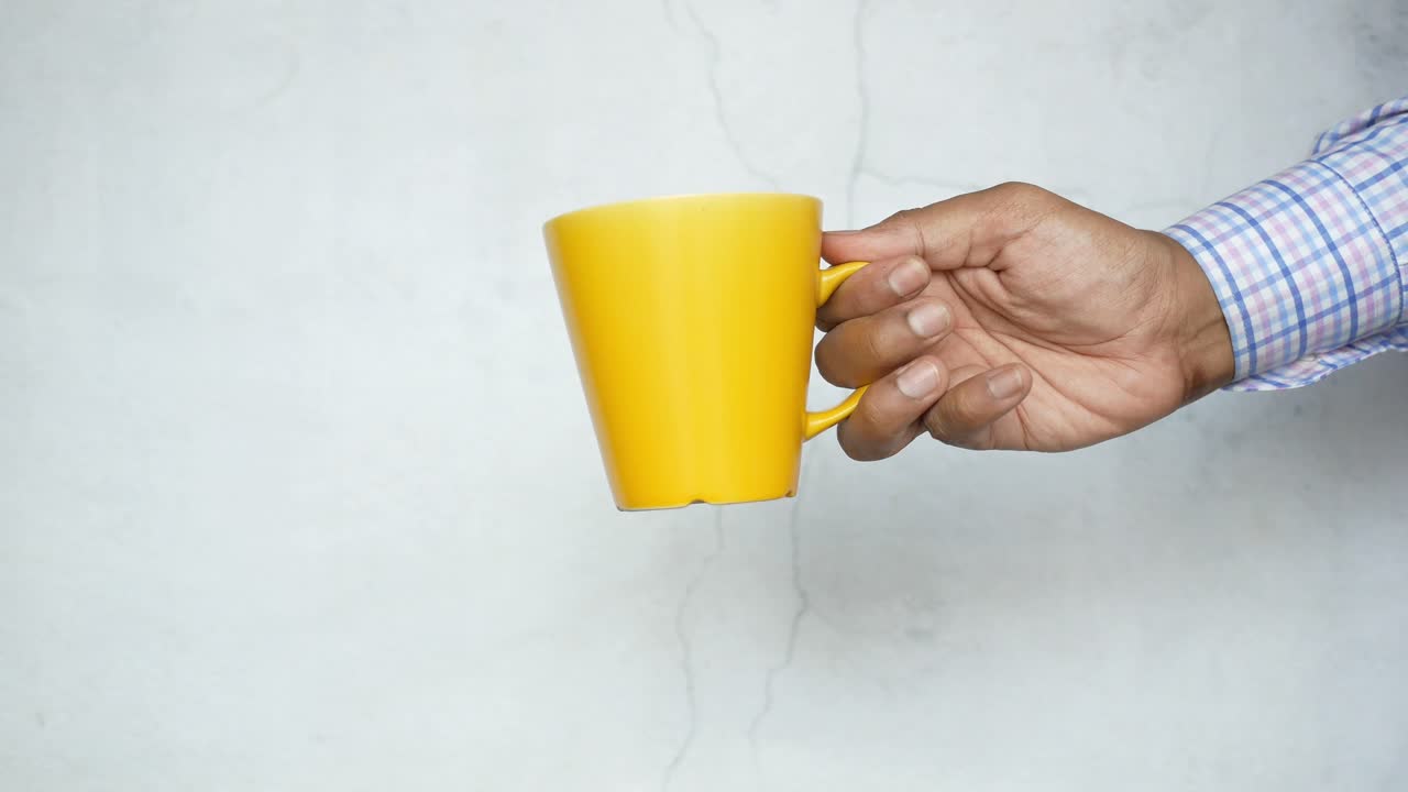 persona que sostiene una taza amarilla