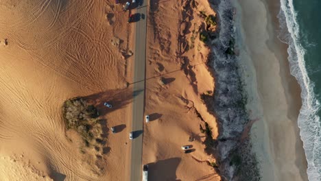 Aerial-drone-bird's-eye-top-view-of-the-stunning-Cliffs-of-Cacimbinhas-in-Pipa,-Brazil-Rio-Grande-do-Norte-with-tourists-sand-boarding-as-small-waves-crash-into-the-beach-on-a-warm-summer-day