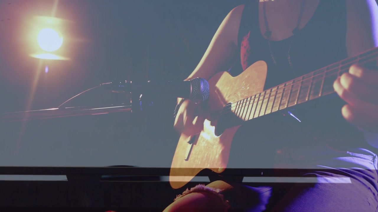 Câmera panorâmica trazendo musicista feminina para o centro, guitarra alinhando-se com o microfone, tocando para um set acústico