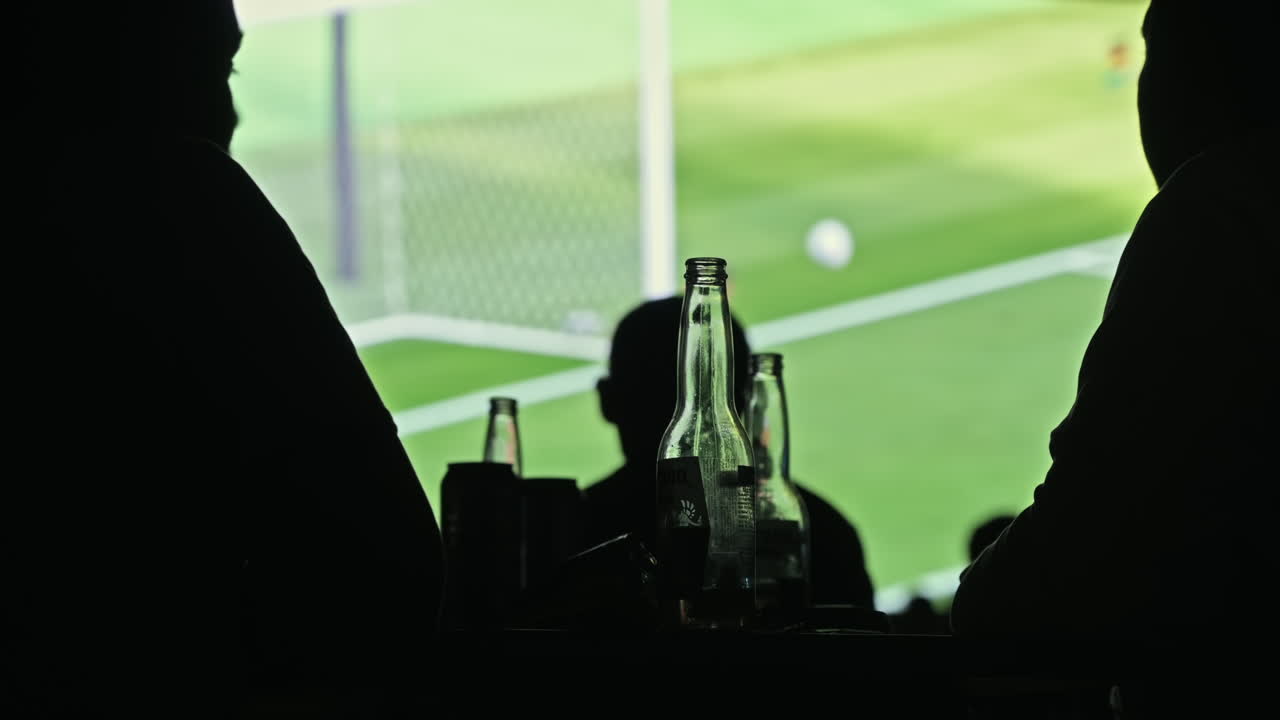 Man drinking beer and watching football at night