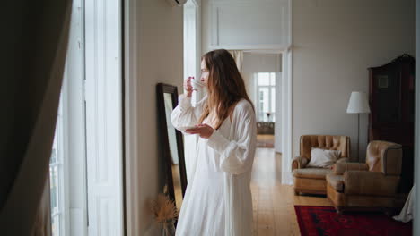 calm woman drinking tea at morning home interior. tender lady watching window