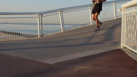 man running on a coastal bridge at sunrise/sunset