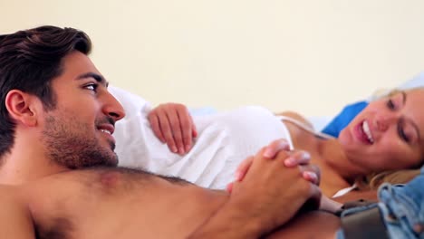 pareja linda acostada en una cama riendo y hablando