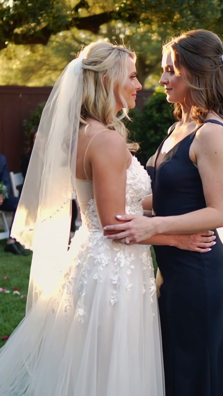 Vertical video: Pulling camera in as brides embracing and leaning at yard wedding gowns