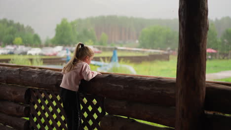 Little-girl-climbs-up-on-log-fence-to-look-at-helicopter