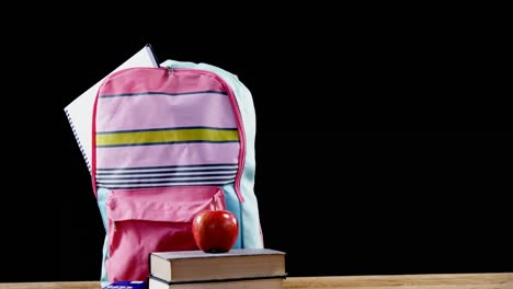 apple on book stack with schoolbag