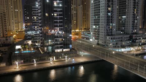 a beautiful timelapse of dubai marina : the boats on the water canal, a highway with cars creating light streaks, tall skyscrapers