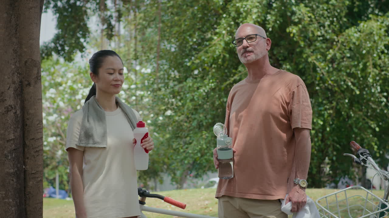 Middle-aged Active People Drinking Water after Exercising in City Park