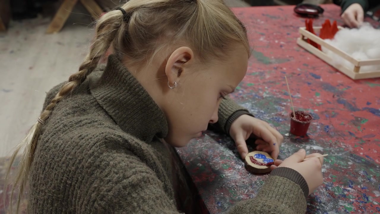 Giovane Ragazza che Dipingere con Cura un Piccolo Ornamento in Legno in uno Studio d'Arte