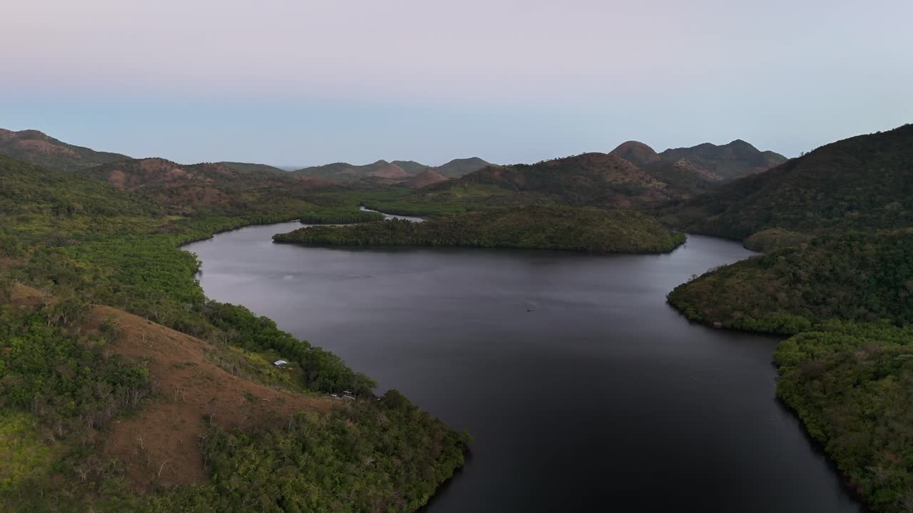 A calm bay inlet surrounded by dense forest and rolling highlands in Sitio Coring, Bay, Culion Island, Philippines, framed by rugged terrain and serene tropical wilderness